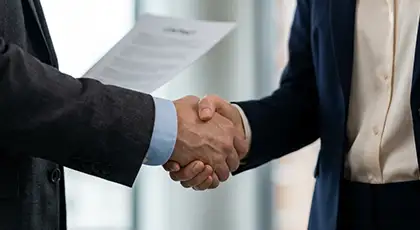 Partially visible woman and man in suits shake hands, while the man holds a blurred contract. AI-generated image.