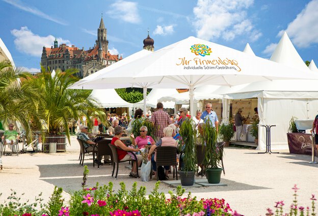 Schneider hospitality parasols of the Easymax model stand in a busy outdoor dining area. People sit underneath, enjoying protection from the sun – ideal for professional use in cafés, restaurants, beer gardens, and hotel terraces.