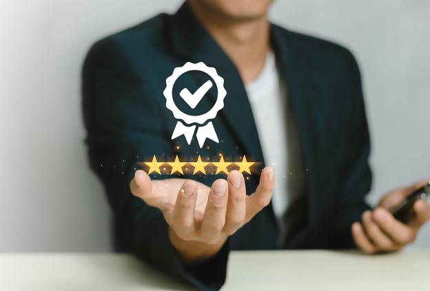 Stock image for certified safety and quality standards: Above an open hand of a person, five yellow stars and a quality seal float – representing UV protection, wind stability and responsible use of parasols.
