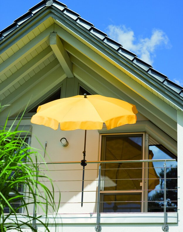 Der Schneider Sonnenschirm Aquila in Premium-Ausführung ist mit einem Schirmhalter Foxi sicher am Balkongeländer befestigt. Das strukturierte Schirmtuch mit Volant spendet stilvoll Schatten bei hohem UV-Schutz – ideal für Balkon, Terrasse und Garten.
