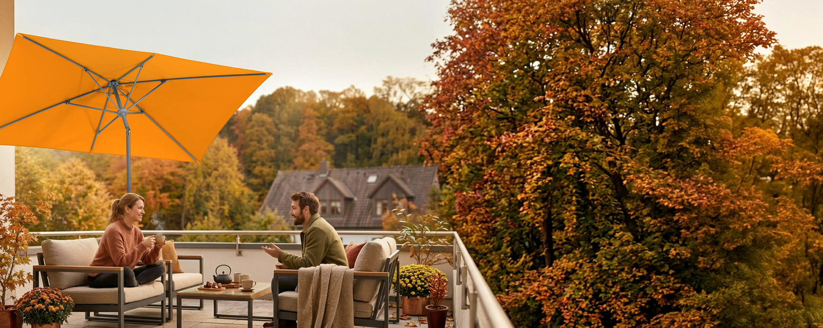 Two people are seated on a lounge on a balcony beneath the Schneider Tunis parasol (270 × 150 cm). In the background, a house is surrounded by trees in their autumn colors. AI-generated image.