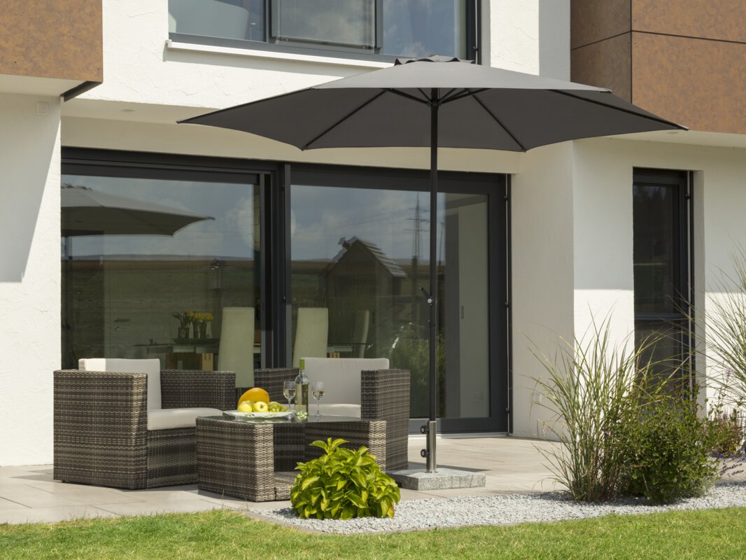 Schneider Sonnenschirm Bergamo in Anthrazit, 300 cm Durchmesser, auf einer Terrasse mit Lounge-Möbeln. Auf dem Tisch befindet sich eine Obstschalte mit einer Flasche und Gläsern. Im Vordergrund kleine Sträucher und Wiese.
