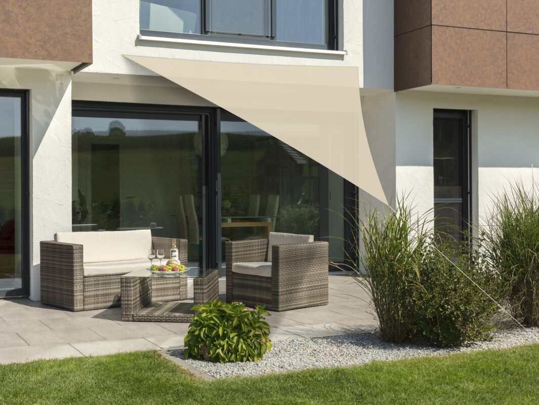 Schneider Sonnensegel Lanzarote in Natur, 360x360x360 cm, gespannt über eine Terrasse mit Lounge-Möbeln. Auf dem Tisch befindet sich eine Obstschale mit einer Flasche und Gläsern. Im Vordergrund kleine Sträucher und Wiese.
