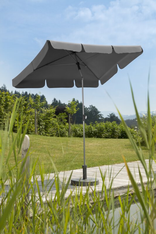 Schneider Sonnenschirm Locarno in Anthrazit, 180x120 cm, auf einer Holzterrasse an einem Naturpool. Im Vordergrund Schilf, im Hintergrund Wiese und verschiede Grünpflanzen.