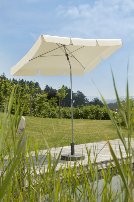 Schneider Sonnenschirm Locarno in Natur, 180x120 cm, auf einer Holzterrasse an einem Naturpool. Im Vordergrund Schilf, im Hintergrund Wiese und verschiede Grünpflanzen.