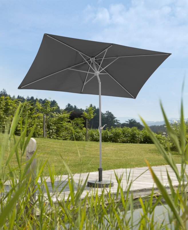 Schneider Porto parasol in anthracite, 300x200 cm, on a wooden terrace by a natural swimming pool. Reeds in the foreground, meadow and various green plants in the background.