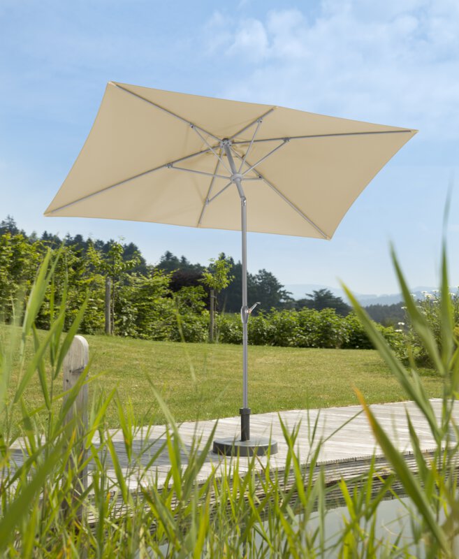 Schneider Porto parasol in ecru, 300x200 cm, on a wooden terrace by a natural swimming pool. Reeds in the foreground, meadow and various green plants in the background.