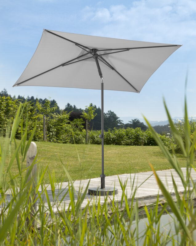 Schneider parasol Sevilla in silver grey, 240x140 cm, on a wooden terrace by a natural swimming pool. Reeds in the foreground, meadow and various green plants in the background.